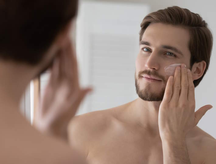 Skincare for Men: A Beginner's Perspective, Close,Up,Mirror,Reflection,Satisfied,Young,Man,Applying,Face,Moisturizing
